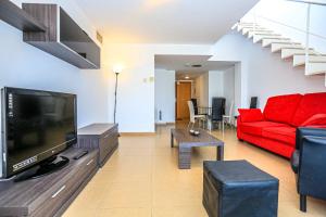 坎布里尔斯Ciutadella Litoral - ONLY FAMILIES的客厅配有红色沙发和电视