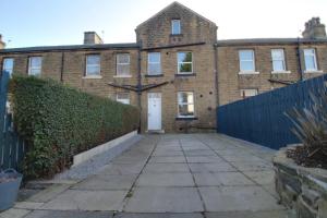 哈德斯菲尔德Lovely 4 Bed House in Huddersfield with parking的旧砖屋,设有围栏和车道