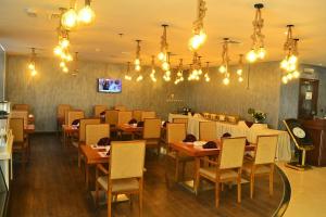 多哈Palm Inn Hotel Doha的餐厅设有木桌、椅子和吊灯。