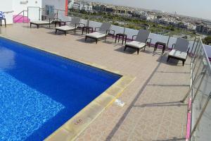 多哈Palm Inn Hotel Doha的一个带椅子的阳台和一个位于大楼内的游泳池