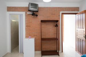 新维索萨Pousada Freitas Alonso的一间设有砖墙的客房,墙上配有电视