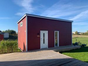 马尔默Your own 30sqm house with kitchen, sauna and loft.的一座红色的小建筑,甲板上设有白色门