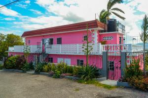 蒙特哥贝Three Palm Villa的粉红色的建筑,前面有栅栏