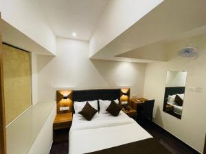 孟买Hotel Hilton Suites的一间卧室配有一张带两盏灯和镜子的床