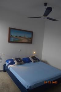 PalmeiraLA VELA的一间卧室配有一张蓝色的床和吊扇