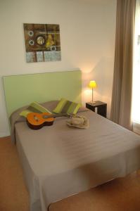 埃屈埃莫维尔阿多尼斯酒店的一间卧室配有一张带吉他的床