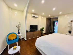 胡志明市Chez Mimosa Corner - New address 90 Đề Thám的一间卧室配有一张床、一台电视和一张蓝色椅子