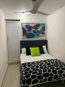 巴兰基亚Hostal Sabanero的卧室配有一张床,墙上挂有绘画作品