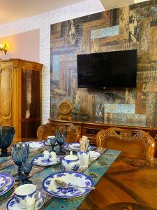 埃里温Shirbakyan Boutique Hotel & Apartments的一间用餐室,配有一张桌子,墙上配有电视
