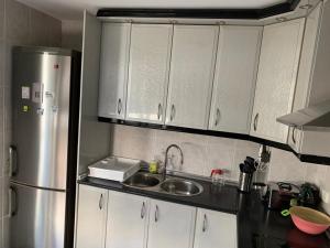 拜纳Apartamento Al Andalus的厨房配有白色橱柜和不锈钢冰箱