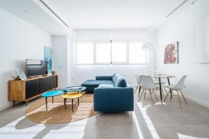 塞维利亚Apartmentos Marqués de Nervion的客厅配有蓝色的沙发和桌子