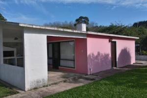 拉佩德雷拉La Rosadita, un escape tranquilo en La Pedrera.的粉红色和白色的建筑,设有车库