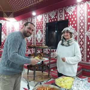 瓦迪拉姆Rum Hatem Camp的站在餐桌旁的男人和女人,一边吃比萨饼