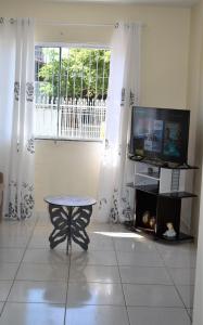 伊塔佩马Casa Aconchegante em Itapema的客房设有桌子、电视和窗户。
