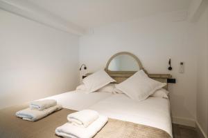 塞维利亚apartamentos montevideo 6的一张白色的床,上面有两张折叠毛巾