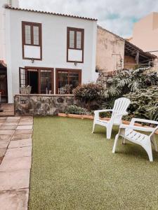 圣克鲁斯-德拉帕尔马Casa La Encarnación的两把白色椅子坐在房子前面的草坪上