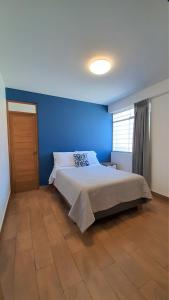 塔克纳Majhu Hostal的一间卧室配有一张蓝色墙壁的床