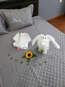 邦美蜀Nhà nguyên căn T Home BMT的床上有两只毛巾动物,床上有鲜花