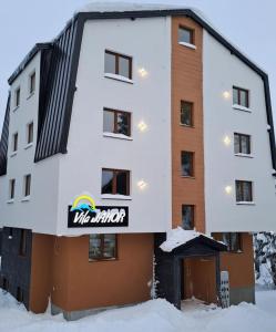 亚霍里纳Vila Jahor Apartman Miro的雪上标有标志的建筑