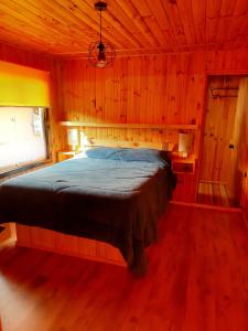 埃尔基斯科PUNTA DE TRALCA SUITES的木制客房内的一间卧室,配有一张床