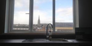 伦敦德里Free Derry Apartments的厨房水槽和享有教堂景致的窗户