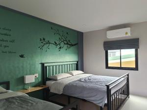 Ban Pak Nam Krasaeบ้าน ชลรพี Baan Chonrapee的一间卧室设有两张床和绿色的墙壁