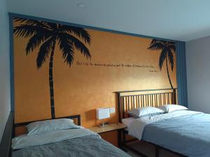Ban Pak Nam Krasaeบ้าน ชลรพี Baan Chonrapee的一间卧室设有两张床和棕榈树壁画