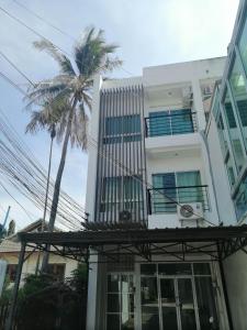 拉威海滩Baan7984 Rawai的一座白色的建筑,前面有棕榈树