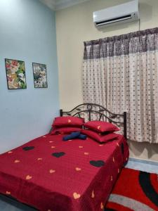 Kampong Tanjong GelamMUAZDIANA HOMESTAY di KUALA NERUS, GONG BADAK的一间卧室配有一张带红色棉被的床和窗户。