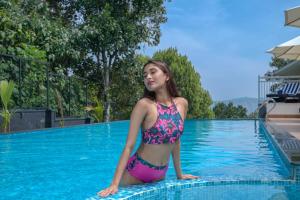 蒙纳Sprise Munnar Resort and Spa的坐在游泳池边的比基尼的女人