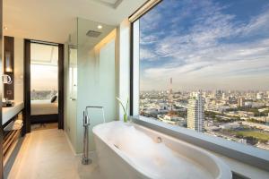 曼谷易思廷大酒店帕亚泰的带浴缸的浴室,享有城市景观