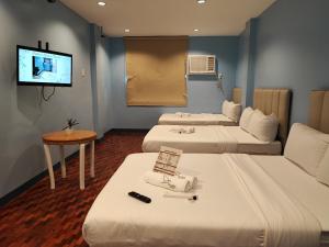 马尼拉Glory Hotel Cubao的一间酒店客房,设有三张床和一台平面电视