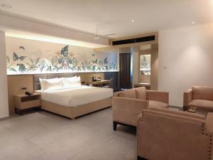 维沙卡帕特南Signature Hotels的一间卧室配有一张床、一张沙发和椅子
