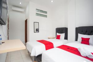 巨港RedDoorz at Jalan Bangau Palembang的配有白色墙壁和红色枕头的客房内的两张床