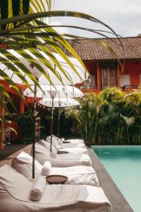 乌鲁瓦图The Room Padang-Padang的游泳池旁一排带遮阳伞的白色躺椅