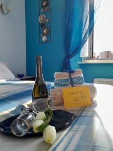 菲乌吉La Casa di Carta FIUGGI的床上的一瓶葡萄酒和玻璃杯