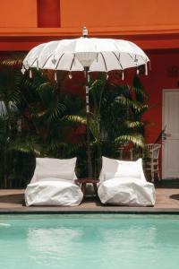 乌鲁瓦图The Room Padang-Padang的两个白色枕头坐在泳池旁的伞下