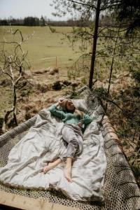 BūtingėNature calls - tree tents的躺在田野吊床上的女人