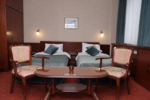 贝尔格莱德宫殿酒店 的酒店客房带两张床和一张桌子以及椅子。