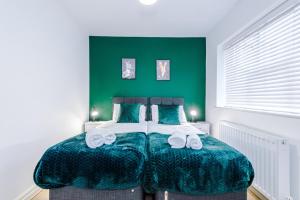 曼彻斯特Lovely 3 Bed house - Park Lane的一间卧室配有一张带绿色墙壁的床