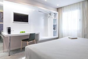 格拉纳达Hotel Maciá Granada Five Senses Rooms & Suites的一间卧室配有一张床、一张书桌和一台电视。