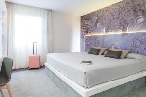 格拉纳达Hotel Maciá Granada Five Senses Rooms & Suites的卧室配有一张白色大床和粉红色的行李箱
