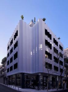 雅典The Social Athens Hotel, a member of Radisson Individuals的一条城市街道上的白色大建筑