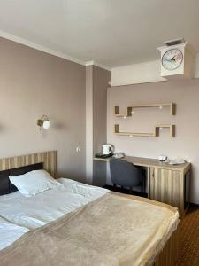 比什凯克Seven Hotel Bishkek的一间卧室配有一张床和一张带时钟的书桌
