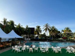 Kampung GurunTHE CLOVE MONT HOTEL的一个带桌椅的游泳池,棕榈树