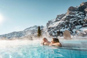 洛伊克巴德瓦尔德豪斯餐厅酒店的坐在雪覆盖的玩具中的热水浴池中的男女