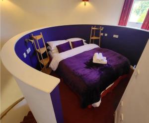 韦尔斯伍基洞酒店的一间卧室配有一张带紫色床单和鞋子的床