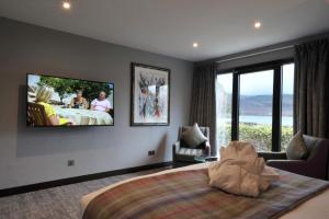 卢斯The Beach House Loch Lomond的卧室配有一张大床,墙上配有电视