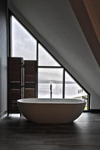 卢斯The Beach House Loch Lomond的设有一个大浴缸的大窗户