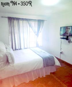 博克斯堡PRIME GUEST HOUSE的一间卧室设有一张带窗户的床和一台电视。